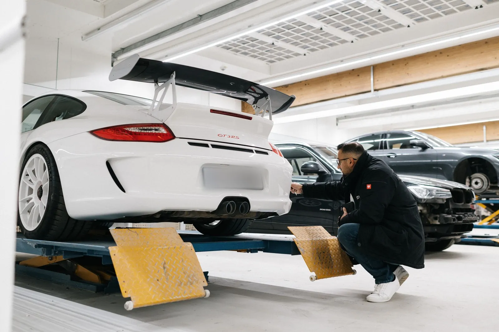 Weißer Porsche 911 GT3 RS auf der Hebebühne, Cüneyt Kadak prüft das Heck